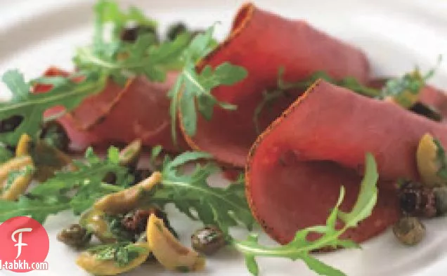 شرائح لحم البقر وسلطة الجرجير مع صلصة الزيتون الأخضر والزبيب